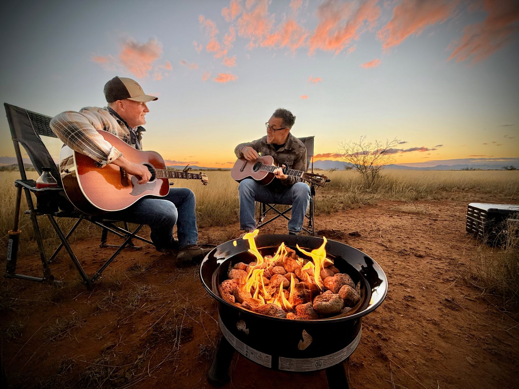 Two guitarists playing by a fire at sunset, Sonoita grasslands